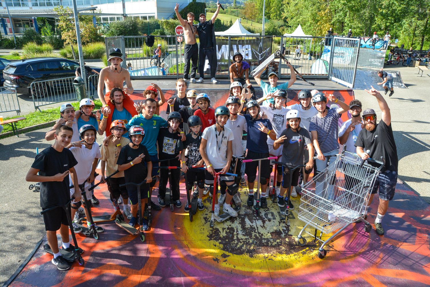 Photo de groupe des participants du Ride Contest, trottinettes à la main, sur la rampe peinte
