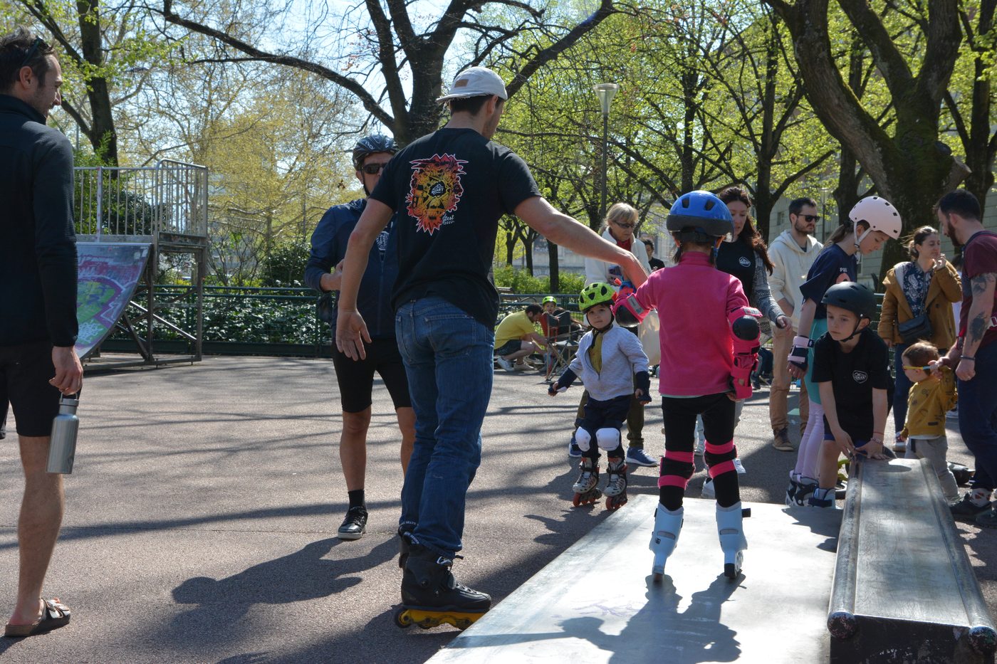 Un encadrant en roller accompagne des enfants casqués et protégés le long d'un module