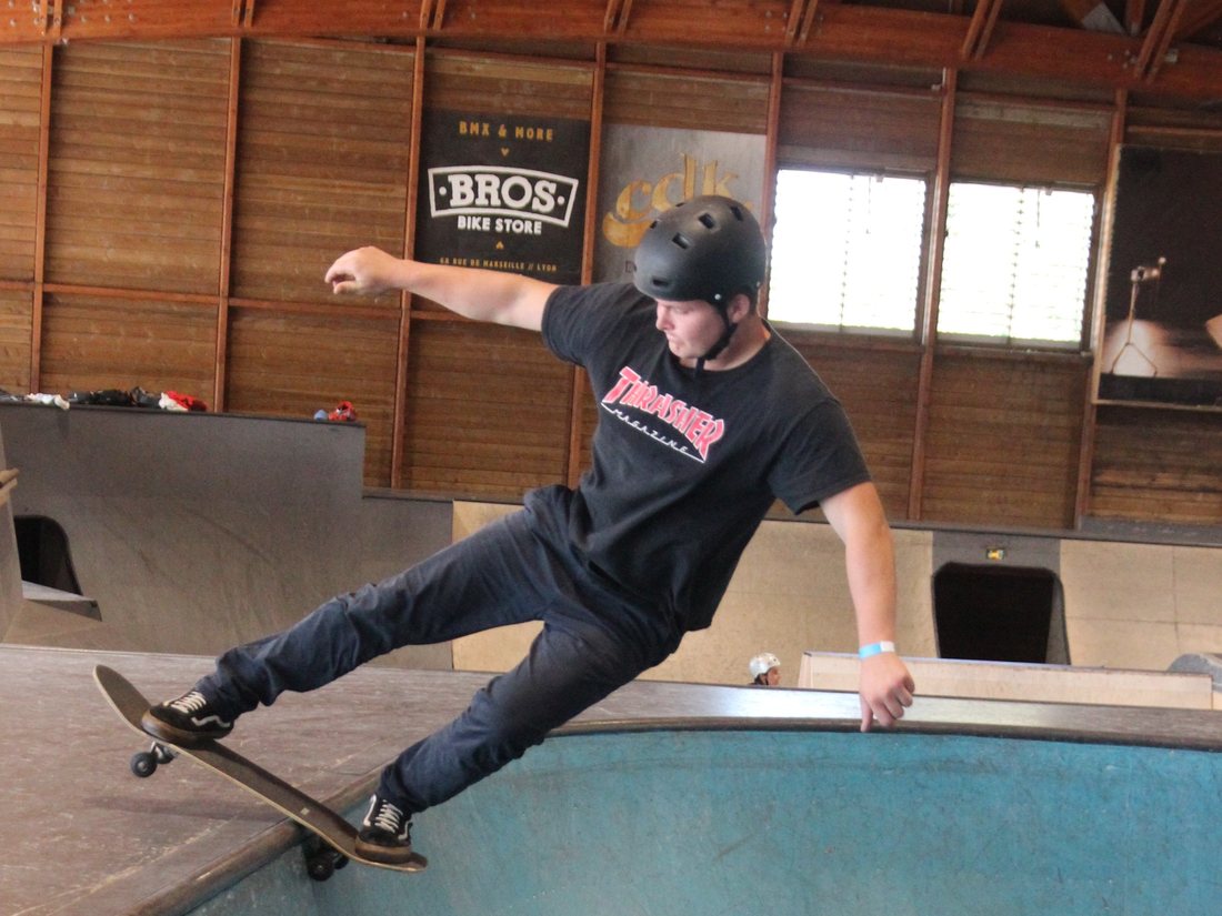 Skateur en appui sur le coping du bowl dans un skatepark couvert
