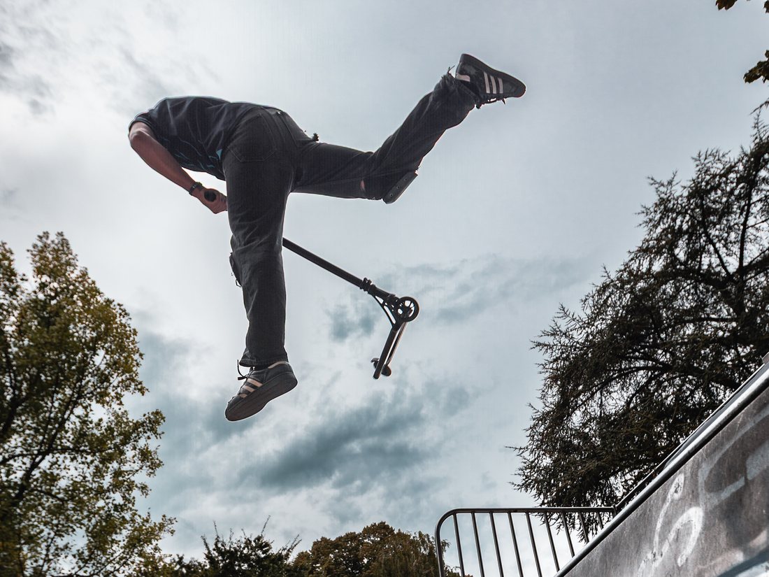 Rider en trottinette freestyle en rotation dans le ciel au-dessus de la rampe