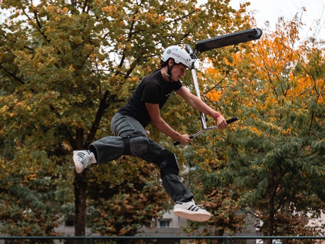Ylan en trottinette freestyle au-dessus d'un module du skatepark