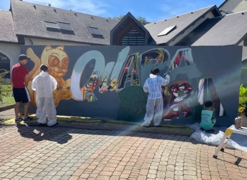 Des jeunes en combinaison peignent une fresque en plein air